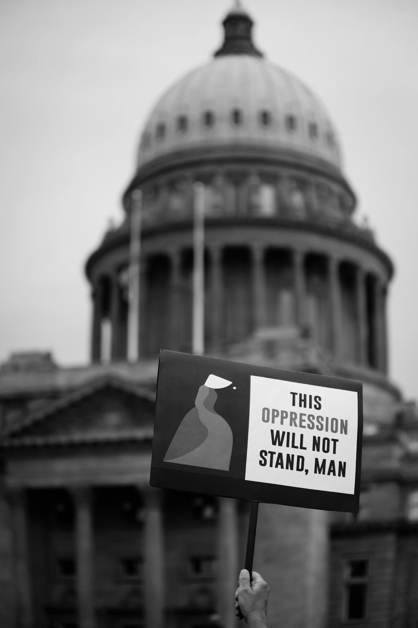 Black and white image of a protest sign against oppression outside a government building.